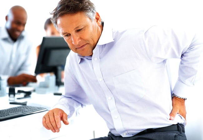 Man ignoring back pain in an office setting.