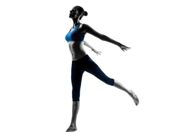 A woman in sportswear performing a rehabilitation dance move against a white background.