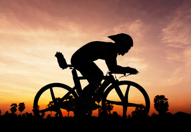 Cyclist silhouette against a sunset background receiving ideal treatment for low back pain.