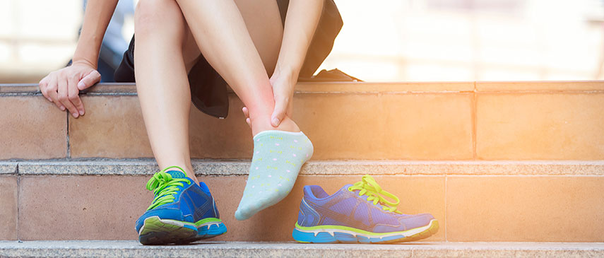 Person sitting on steps putting on socks with sports shoes beside them, ready for their physical therapy session to quickly get back in the game.