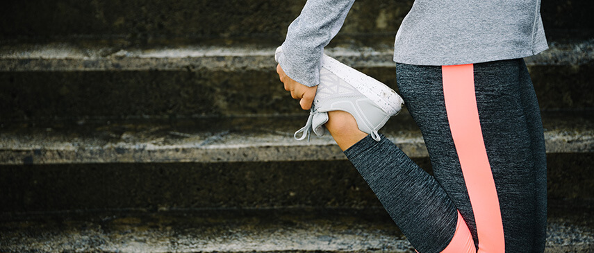 A person performing a leg stretch on stairs, focusing on the calf muscles, wearing sportswear and sneakers to experience the stretching benefits.