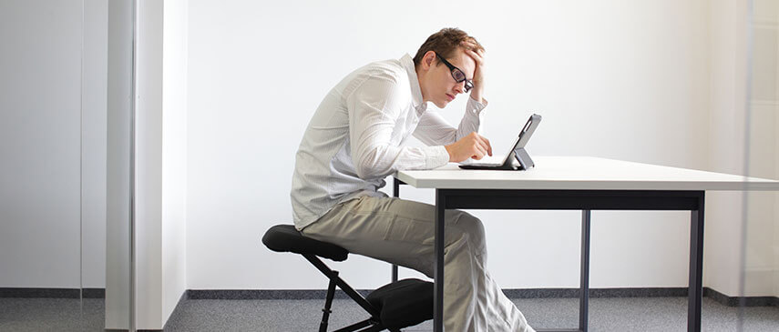 Man in business attire working intently on a tablet at a minimalist desk setup, researching running injuries.