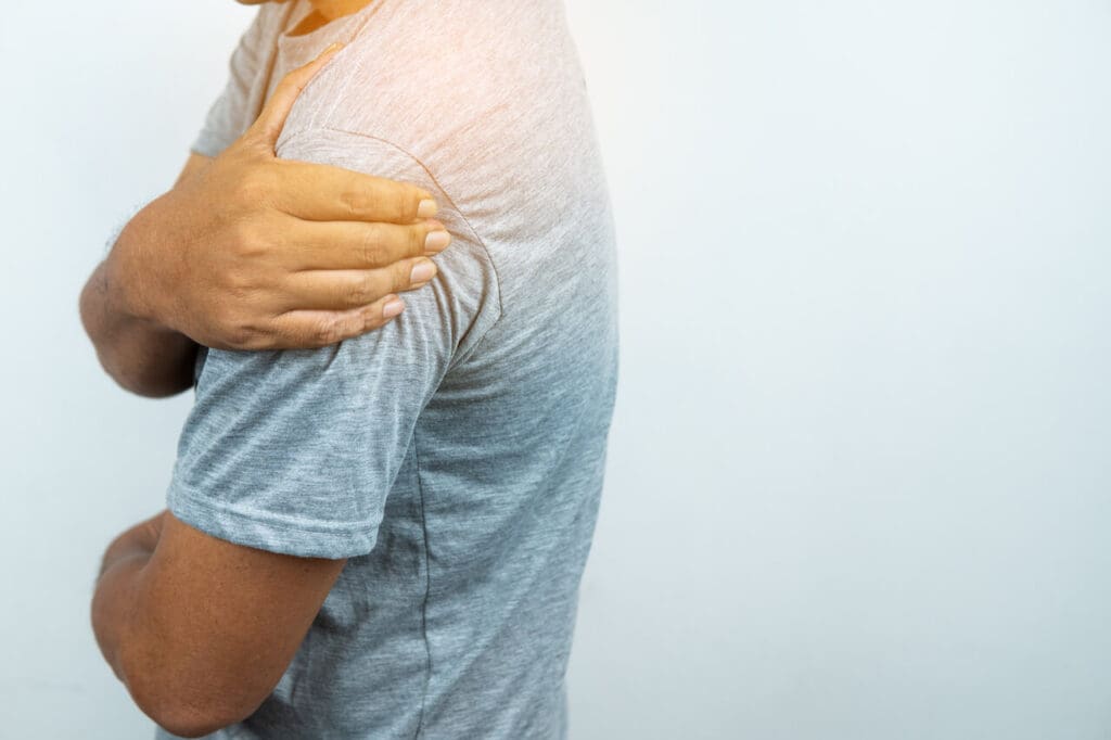 A person holding their upper arm in pain or discomfort due to shoulder pain.