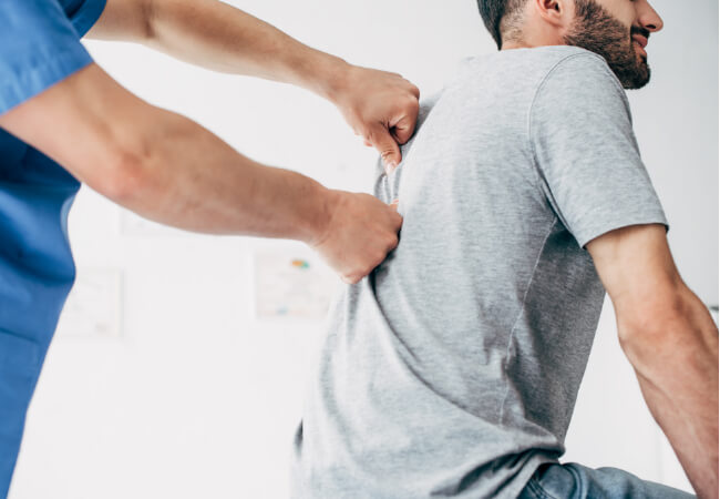 A physical therapy professional examines a patient's back.