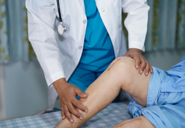 A healthcare professional examining a patient's leg for knee surgery.