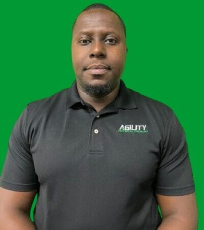 Daniel Jacquet in black polo shirt with "agility" logo standing in front of a green background.