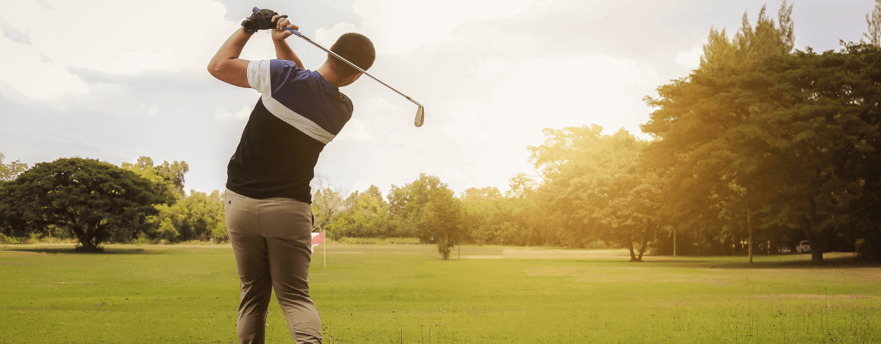 Golfer finishing a swing on a sunny day at the golf course, mindful of preventing golf injuries.