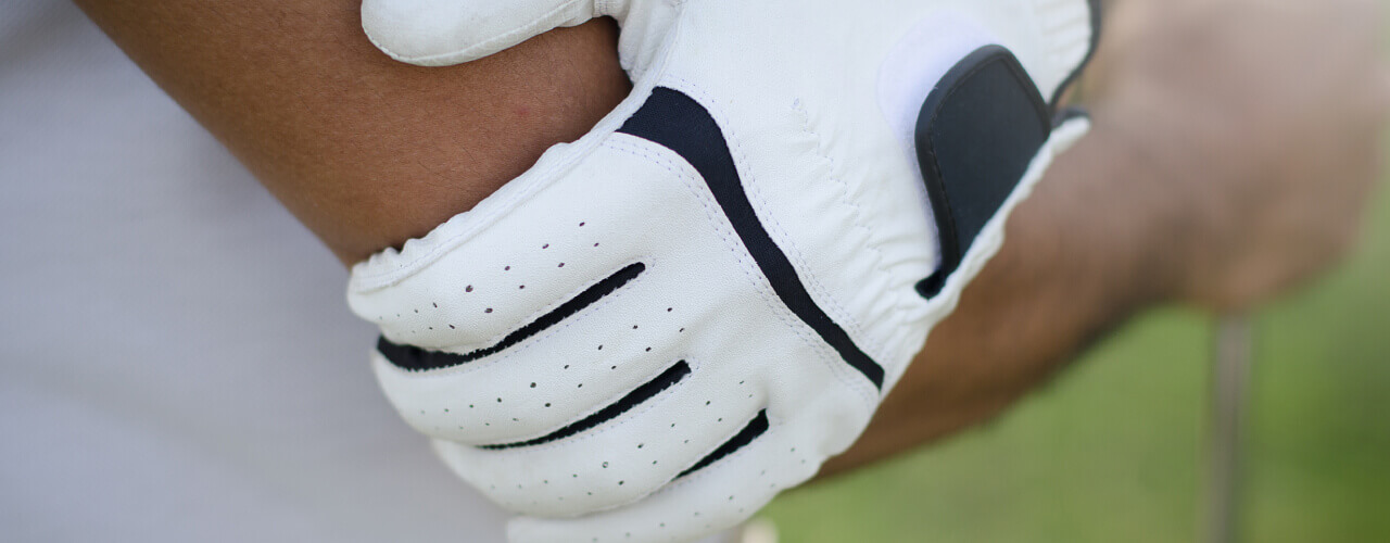 Golfer wearing a white glove carrying a golf club over the shoulder, recovering from a golf-related injury.