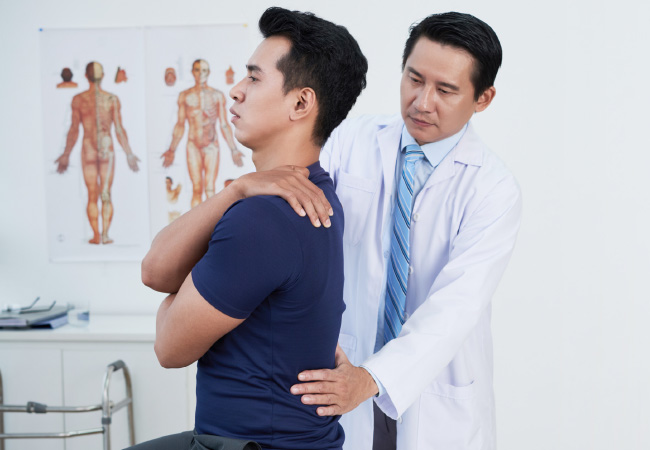 A doctor examining a patient's back pain in a clinical setting.