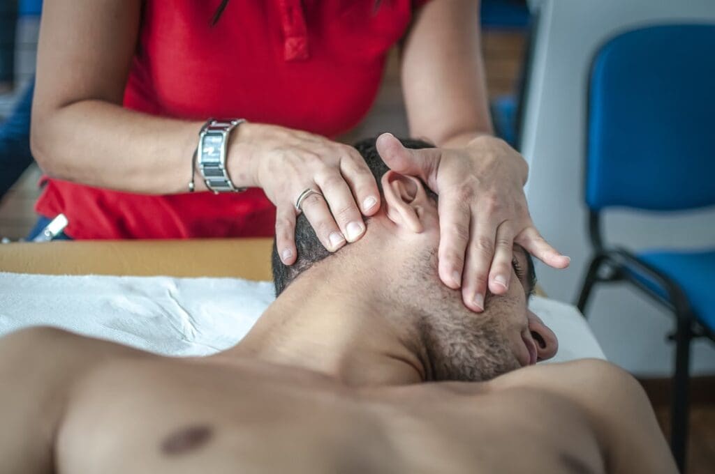 A person receiving a head massage from a therapist to relieve headaches.