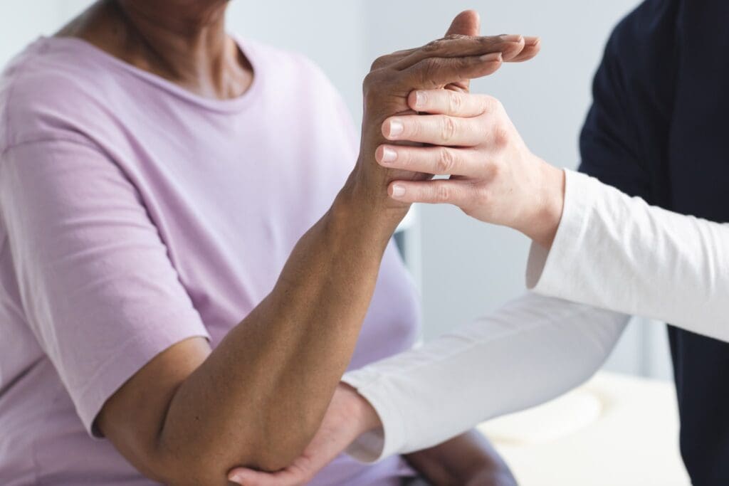 A healthcare professional palpating a patient's wrist during a medical examination, focusing on improving health.