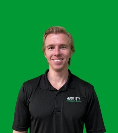 Man in black polo shirt with "Dilbert" logo smiling against a green background.