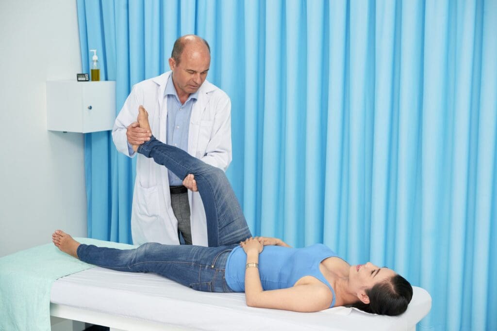 Doctor conducting a physical examination on a patient's leg in a clinical setting to assess symptoms of sciatica.