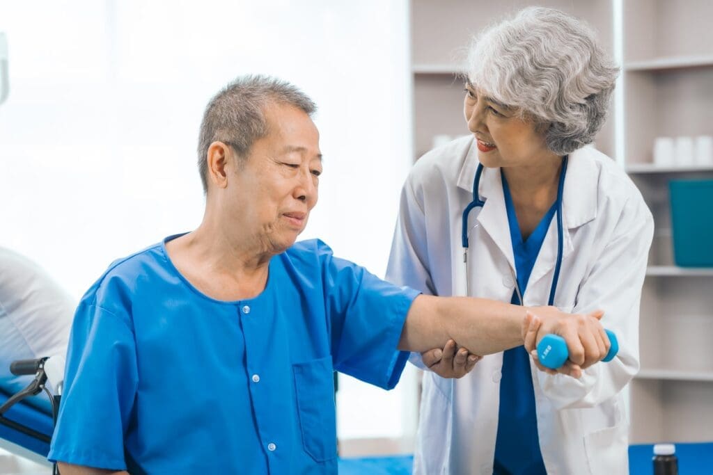 Physiotherapist assisting a senior patient with an arm exercise using a handgrip strengthener to alleviate elbow pain.