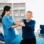 Healthcare professional assisting an elderly patient with exercise for pain management.